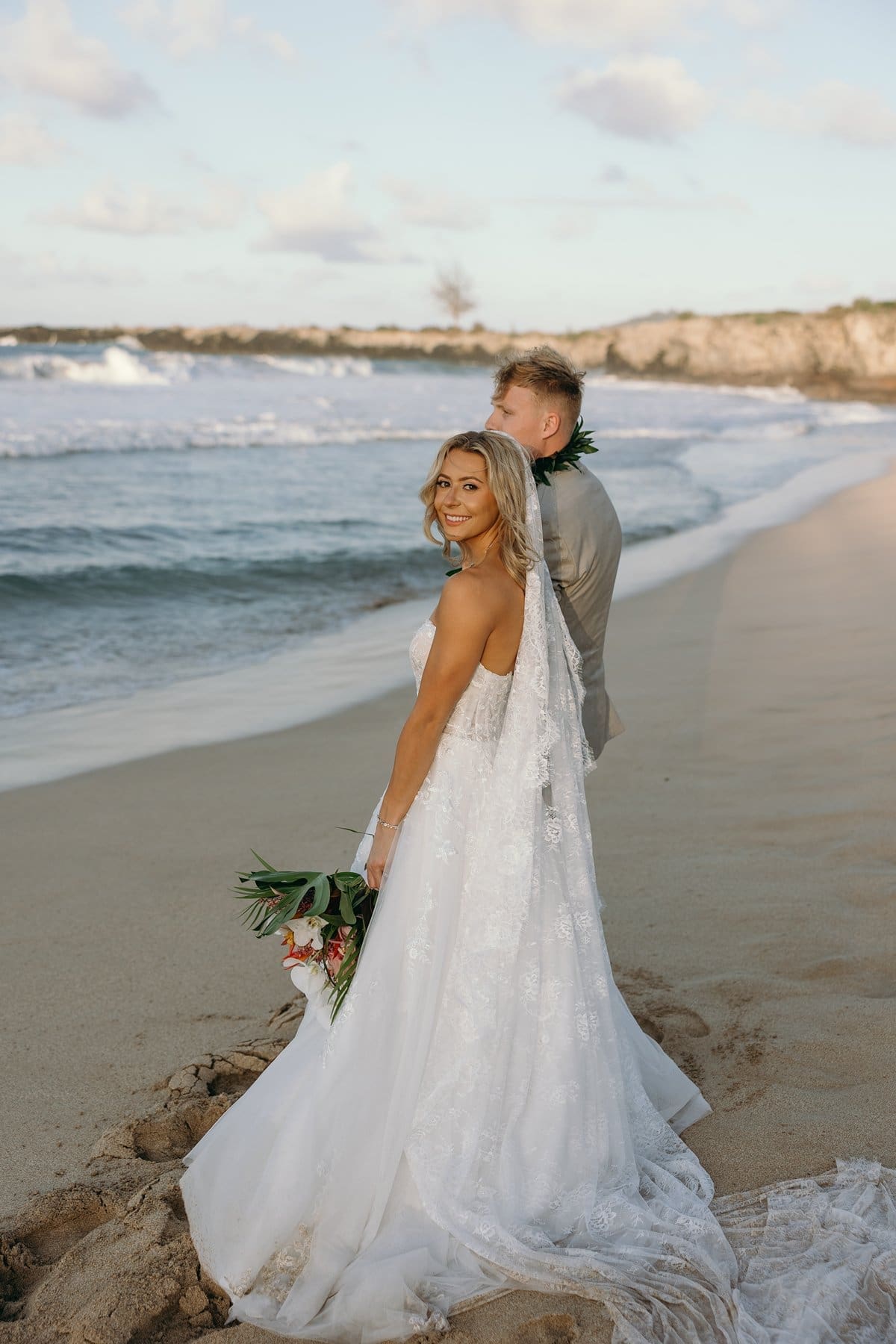 Bride smiling back toward the camera while walking along the shoreline after her Maui elopement ceremony