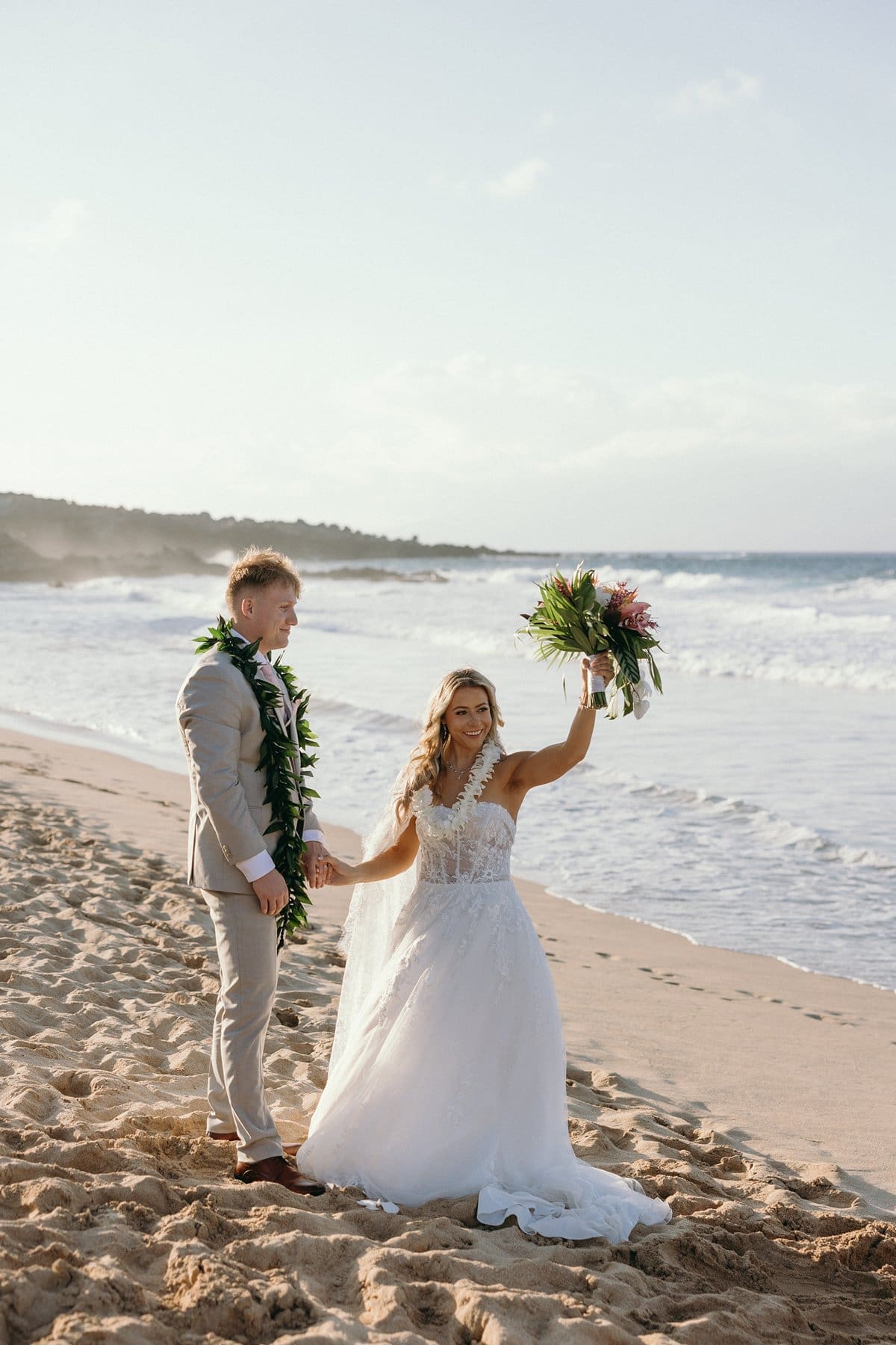 Bride celebrating with her bouquet on the beach after an intimate Maui elopement ceremony