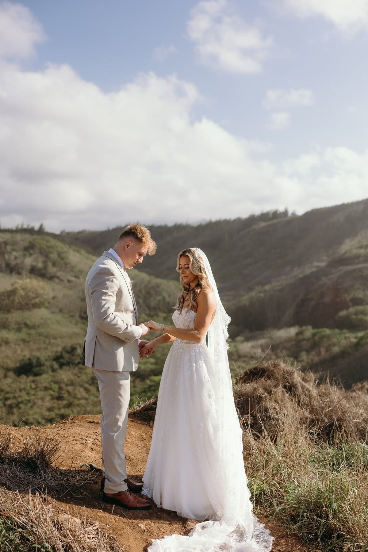Bride and groom exchanging a quiet moment on a bluff overlooking the coastline during their Maui elopement